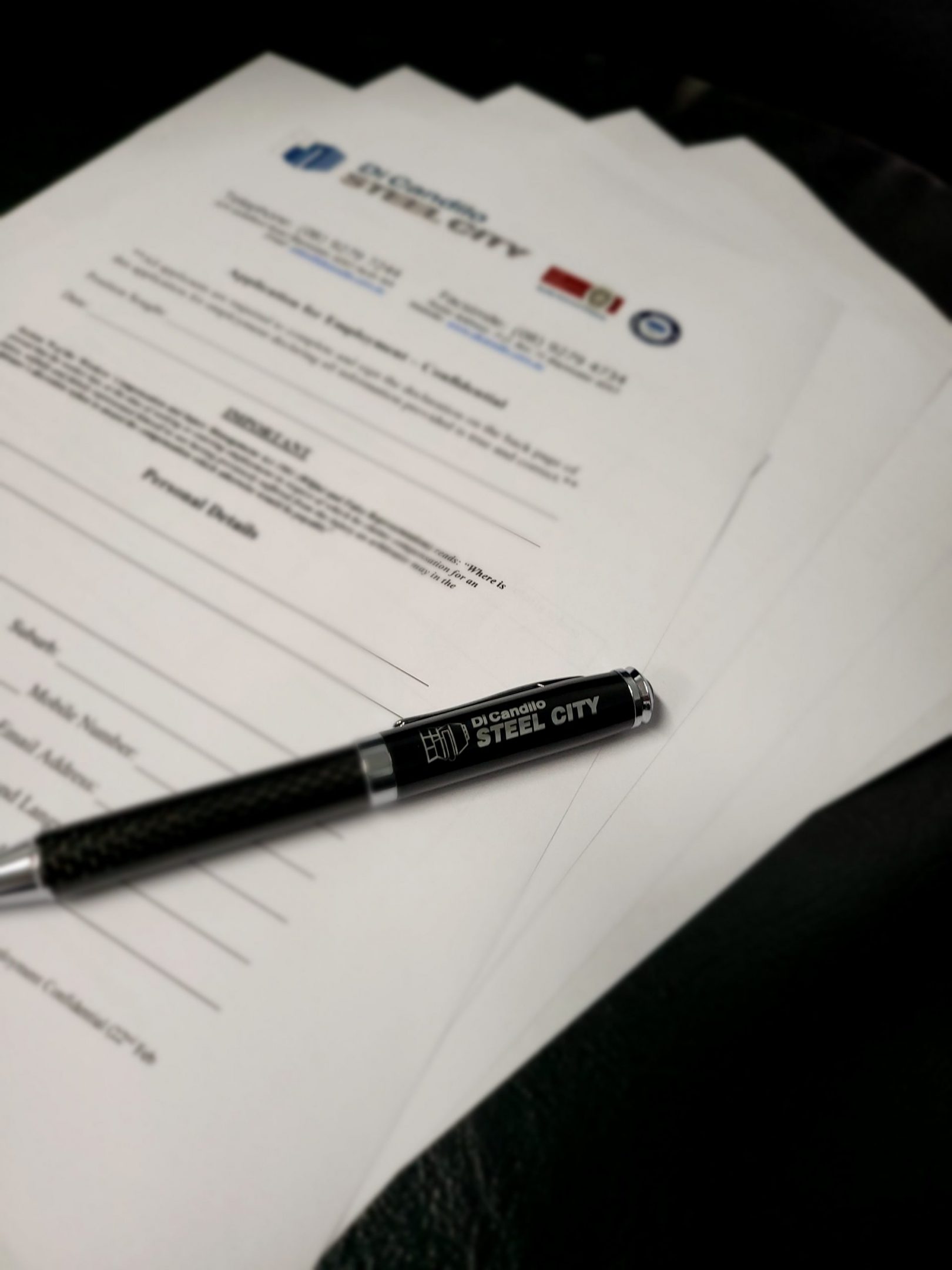 Job application forms with a branded Di Candilo Steel City pen.